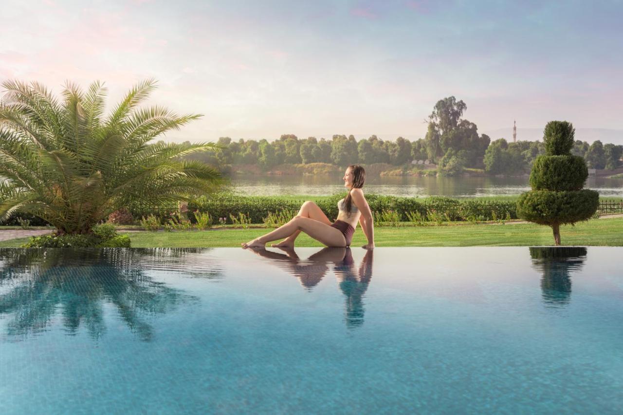 Jolie Ville Hotel & Spa Kings Island Луксор Экстерьер фото A woman sitting on the edge of a pool
